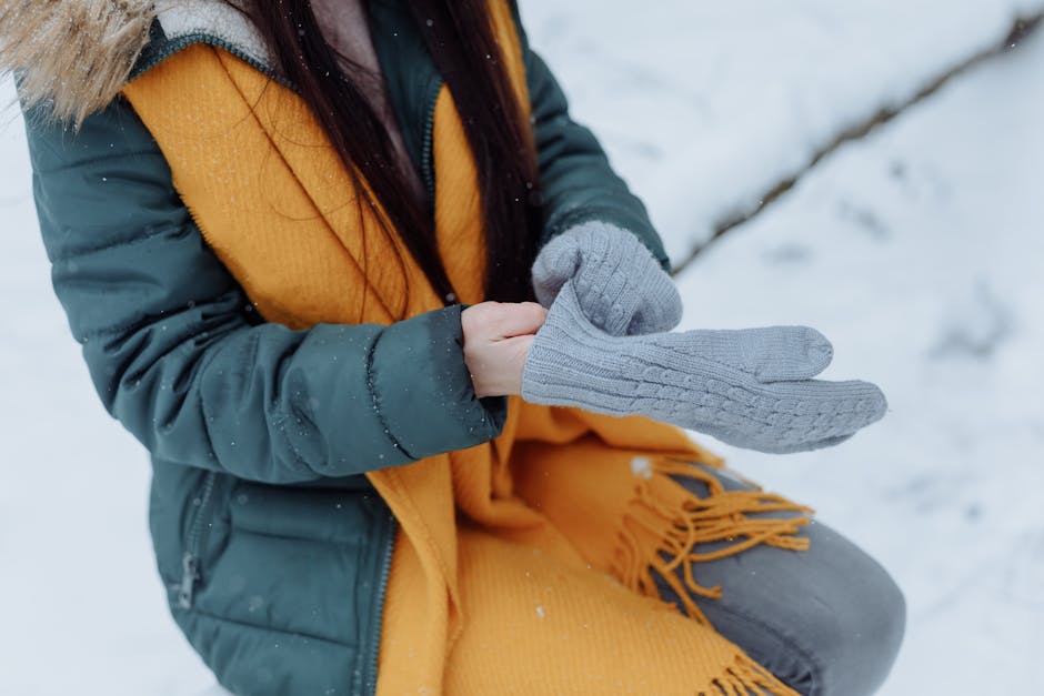 Close-up of cozy knitted mittens and scarf with snow