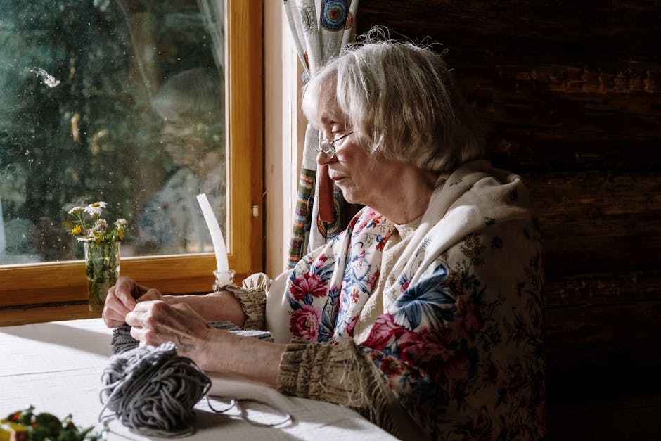 Elderly Russian woman knitting by window