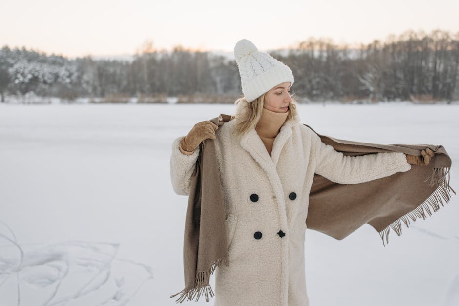 elegant woman in a warm winter coat, scarf and hat against snowy backdrop