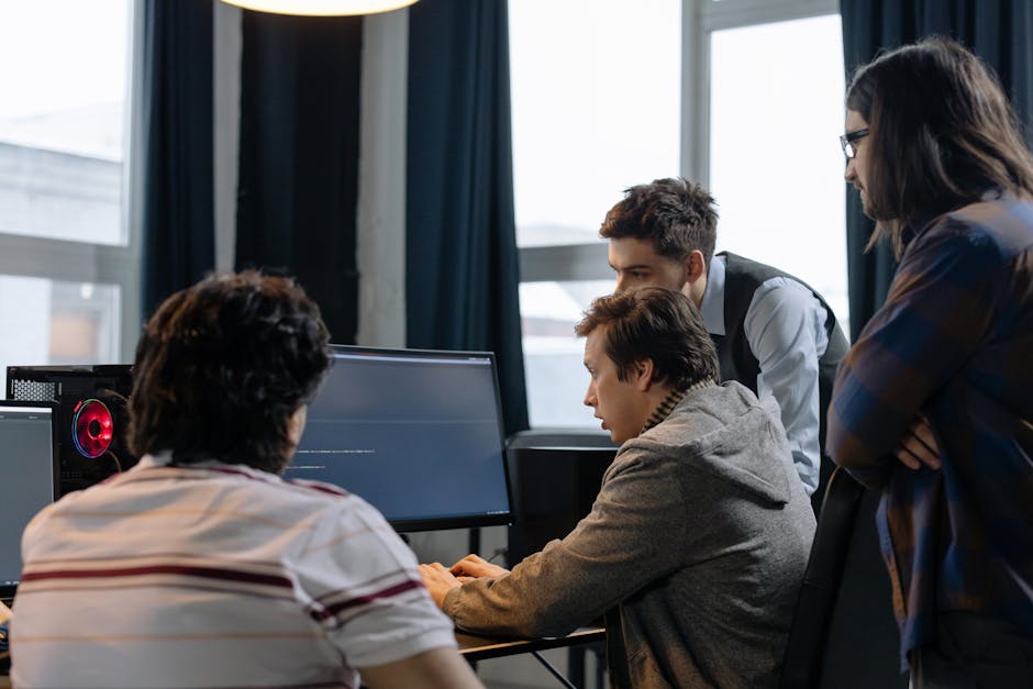 Group of diverse young professionals collaborating on a tech project with screens showing AI code